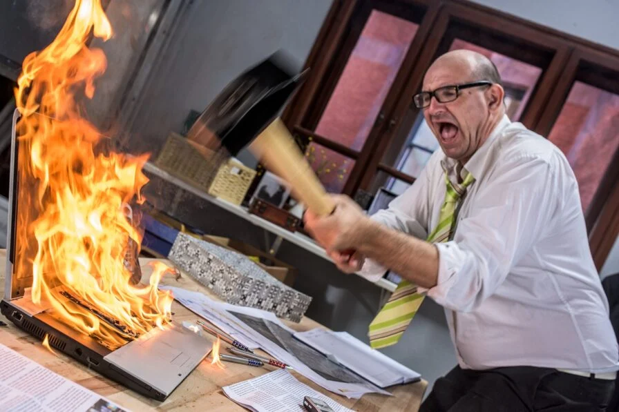 Businessman smashing flaming laptop with large hammer {{brizy_dc_image_alt imageSrc=